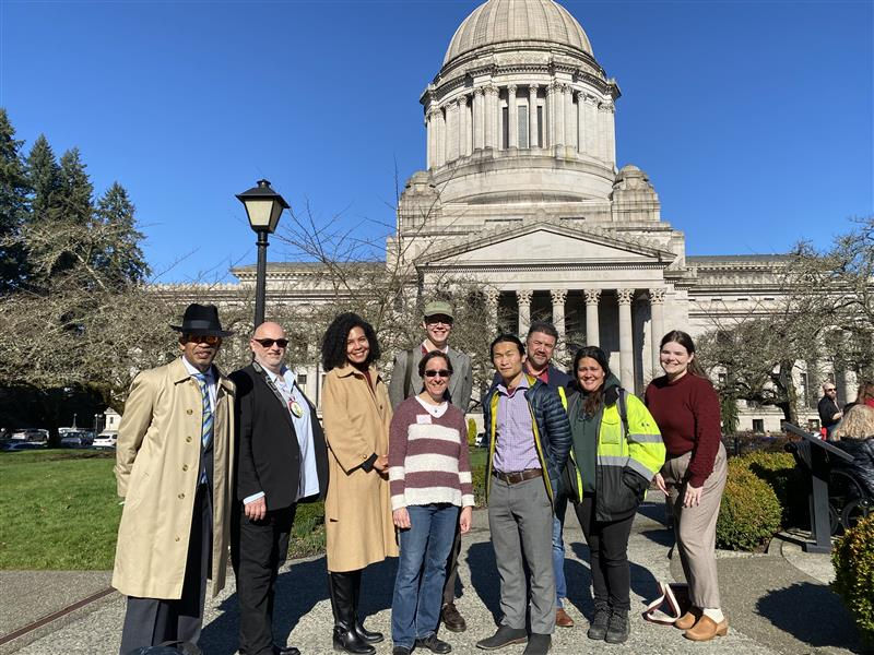 a group of nine advocates standing in front of the washington state legislative building