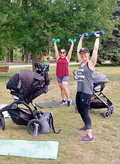 Stroller Fitness class at St. Vital Park in Winnipeg, Manitoba. Two moms are working out with their babies in strollers. The group fitness class is outside. 