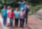 Grupo da equipe sorridente em área externa arborizada.