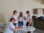 Quatro mulheres da equipe sorrindo ao redor de uma mesa.
