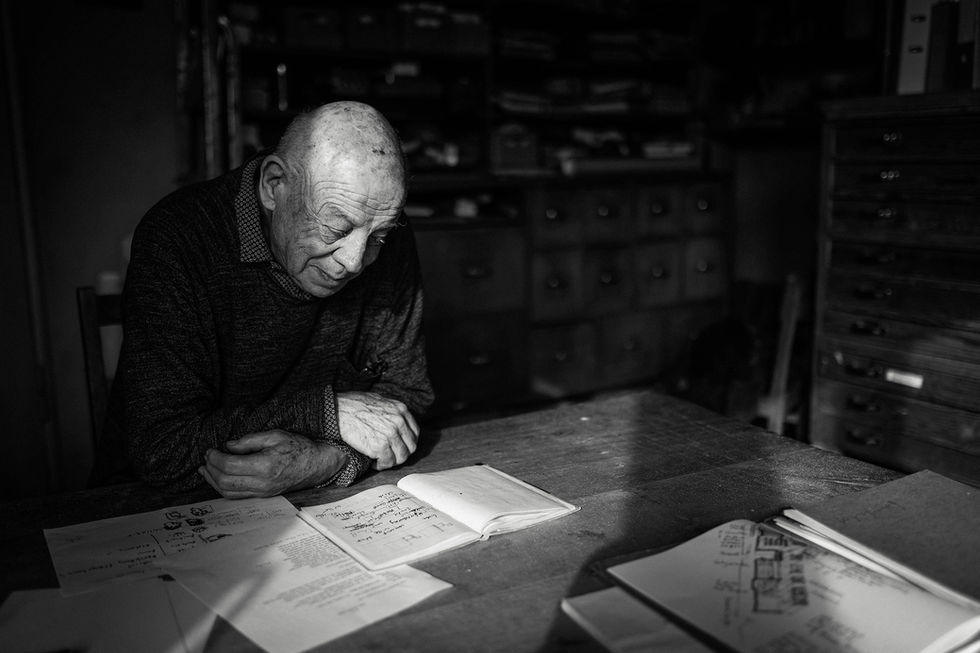 Schwarzweißportrait eines Mannes, der Zeichnungen betrachtet an seinem Arbeitstisch