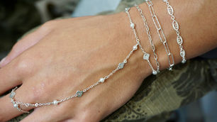 Silver permanent hand chain and layered bracelet stack worn by a client