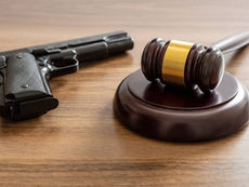 Handgun and judge’s gavel resting on a wooden table, symbolizing firearm law and legal regulation in the United States.