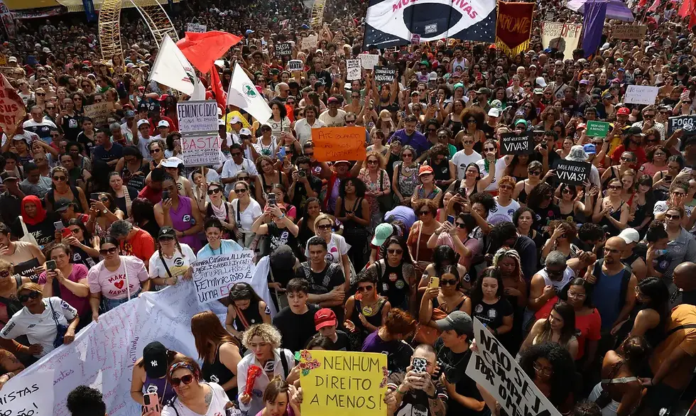 ssa é uma foto aérea de um grande ato contra o feminicídio e a violência contra a mulher, provavelmente na Avenida Paulista (São Paulo), pelo volume de pessoas e pelos elementos característicos.Algumas das frases mais visíveis nos cartazes e faixas:FEMINICÍDIO É CRIME HEDIONDO BASTA! NEM UMA A MENOS! NÃO É NÃO! MULHERES VIVAS! ATÉ QUANDO VÃO NOS MATAR? FEMINICÍDIO É UMA PORRA NENHUM DIREITO A MENOS! NÃO SE CALLE! DENUNCIE JUSTIÇA POR TODAS MACHISMO MATA MINHA VIDA IMPORTA TAINARA VIVE (referência ao caso recente da mulher arrastada em SP) FOI FEMINICÍDIO, NÃO CRIME PASSIONAL Muitas pessoas vestem roxo (cor símbolo da luta feminista), há bandeiras roxas, vermelhas e do Brasil, e o clima é de indignação coletiva com cartazes erguidos bem alto. A multidão ocupa toda a largura da avenida e se perde de vista.
