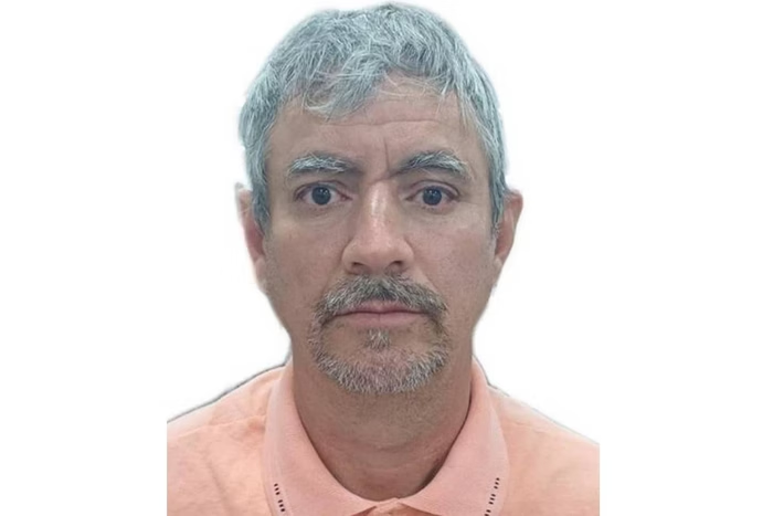 Foto 3x4 do tio de Michelle Bolsonaro, um homem de meia idade, grisalho, com sobrancelhas grossas e labios finos, caucasiano.