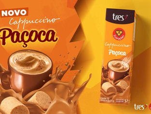 Câpsulas de café cappuccino Pacoca, novo sabor da marca Tres, em destaque na embalagem com bebida quente, biscoitos e chocolate em fundo laranja.