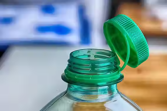 Imagem de uma garrafa de plástico com tampa verde, utilizada para armazenar medicamentos ou suplementos. Ideal para quem busca segurança na conservação de remédios.