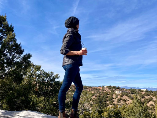 A woman standing atop a log looking out at the view