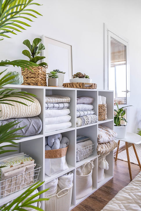 bed-linens-neatly-folded-white-wooden-cupboard-shelves-with-potted-plants-scandi-minimalis