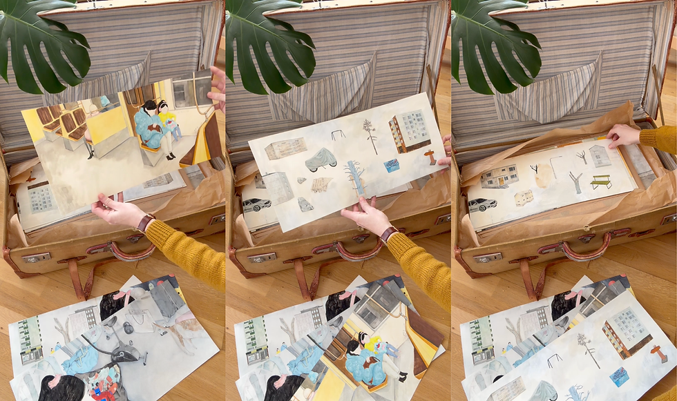 Hands lifting illustrated prints from an open vintage suitcase, showing delicate watercolor scenes of urban buildings, trees, and people.