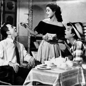a black and white photo of two men and a woman sitting at a table