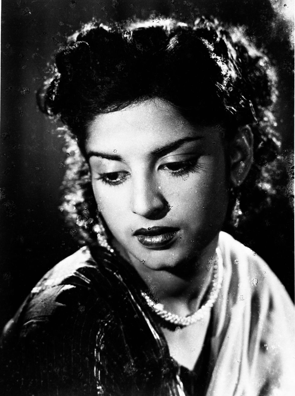 a black and white photo of a woman wearing a pearl necklace