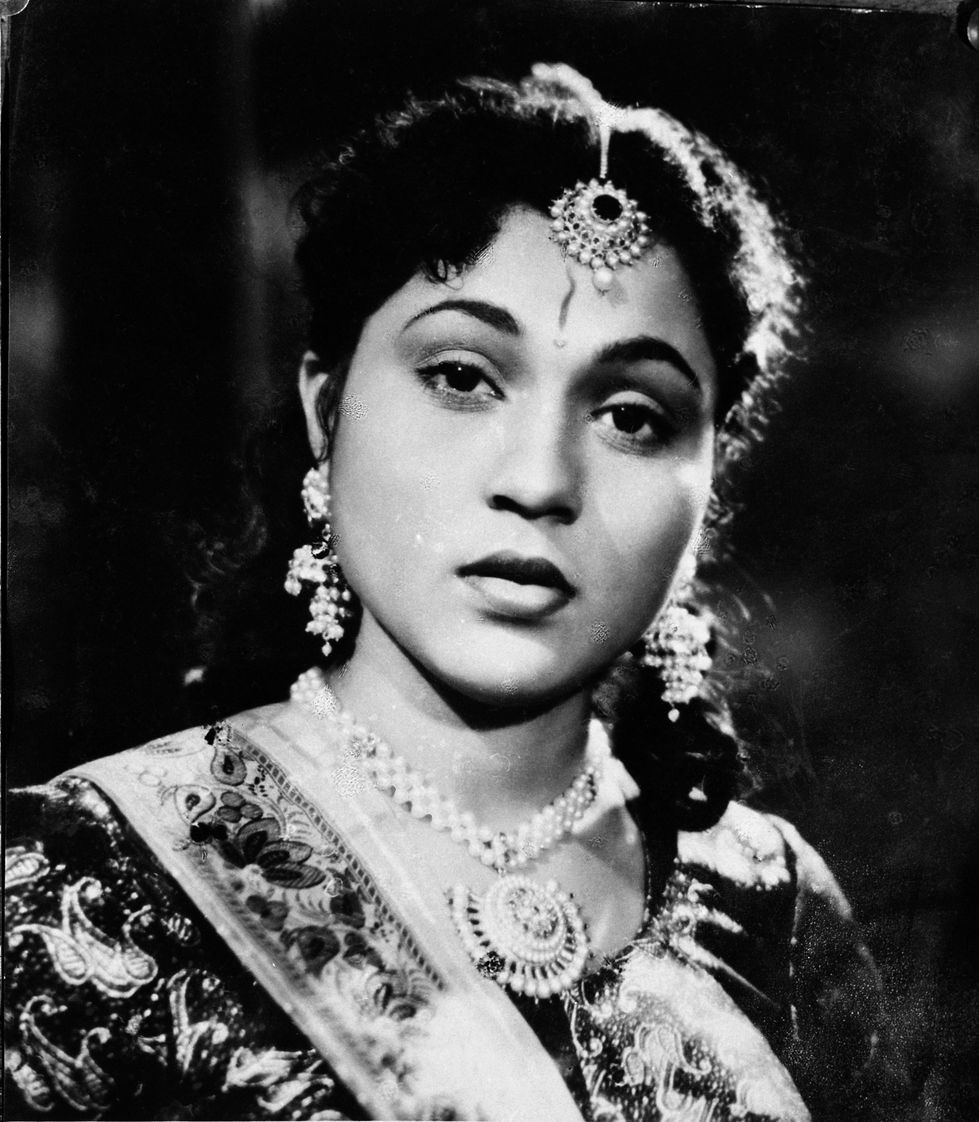 a black and white photo of a woman wearing a necklace and earrings