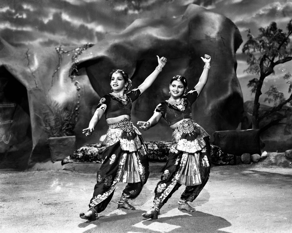 two women are dancing in front of a large rock