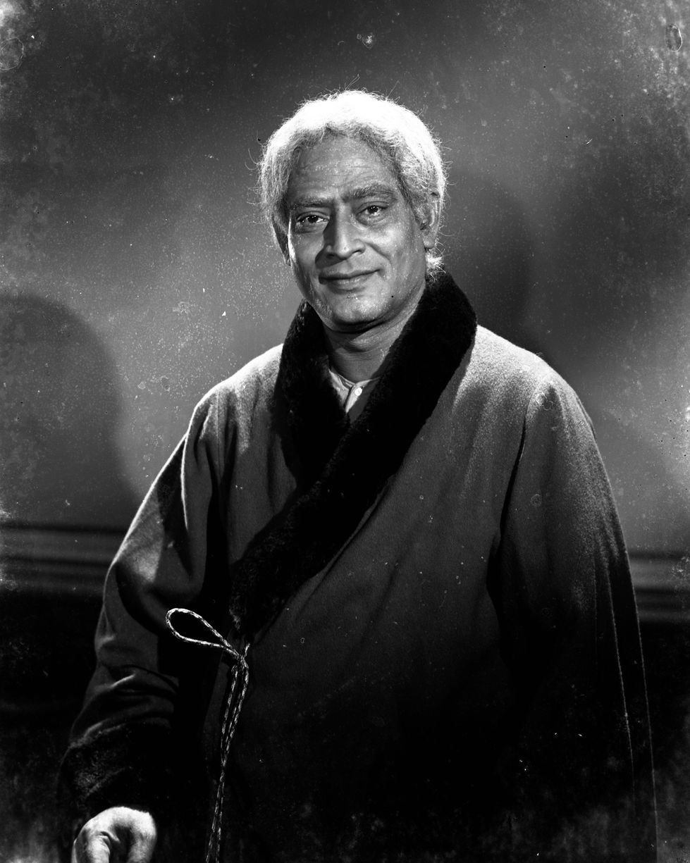 a black and white photo of a man wearing a fur coat