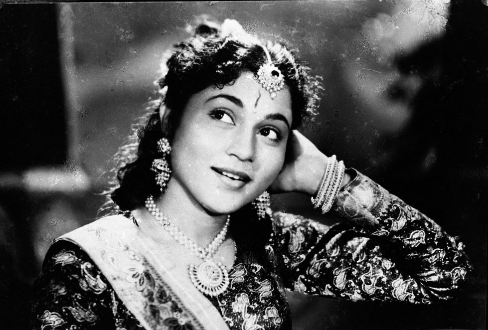 a black and white photo of a woman wearing a necklace and earrings