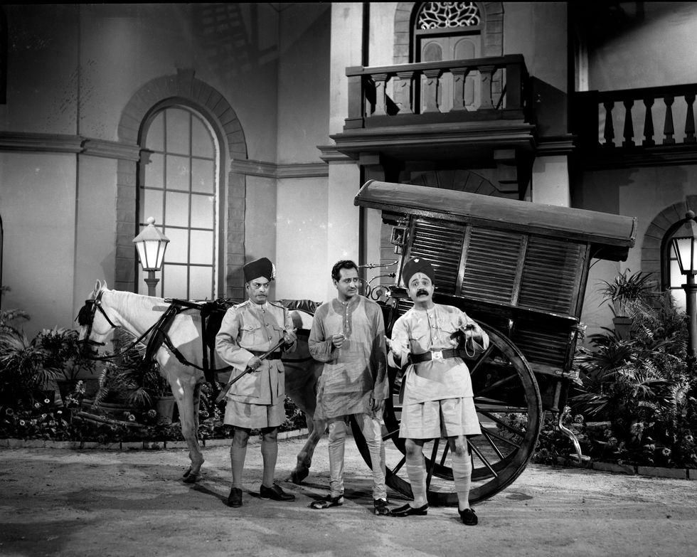three men are standing in front of a horse drawn carriage