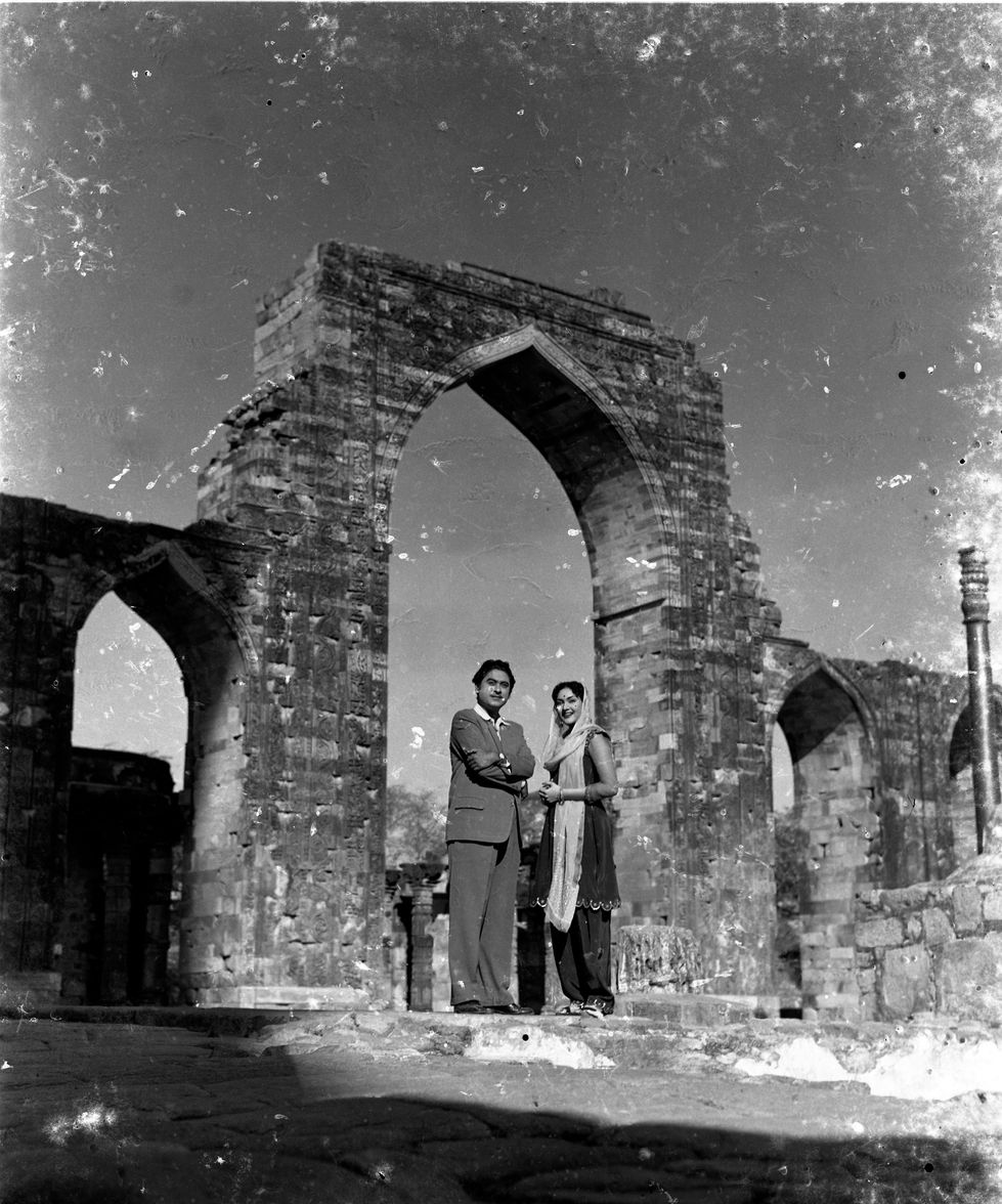 a man and woman standing in front of a stone archway