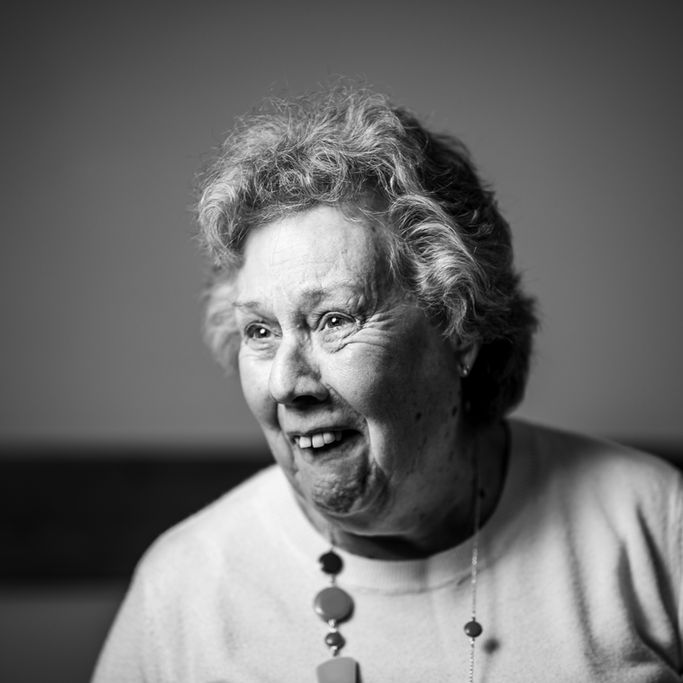 Elderly woman laughing warmly in black and white portrait, photographed by Aemilia Cumberland