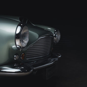In this Aston Martin series, Aemilia Cumberland captures the elegance and heritage of these iconic British automobiles with a refined eye for detail and craftsmanship. Each image celebrates the timeless allure of Aston Martin, focusing on models like the DB4, DB2R, and V12 Vantage, meticulously restored to their former glory at Nicholas Mee. Cumberland’s compositions emphasize the graceful curves, polished surfaces, and intricate details of these classic cars, transforming each vehicle into a work of art. Her use of light accentuates the rich textures of leather interiors and gleaming exteriors, evoking a sense of luxury and prestige that Aston Martin has symbolised for decades. This series is a tribute to the brand’s legacy, capturing the essence of high-performance elegance and British automotive heritage.