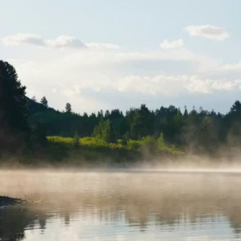 A misty lake overlooking trees and hills