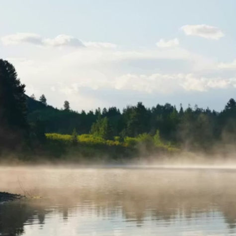 A misty lake overlooking trees and hills