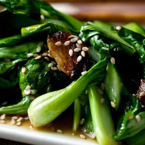 A garlic ginger stirfry with bok choy and spinach and mushrooms piled on a plate