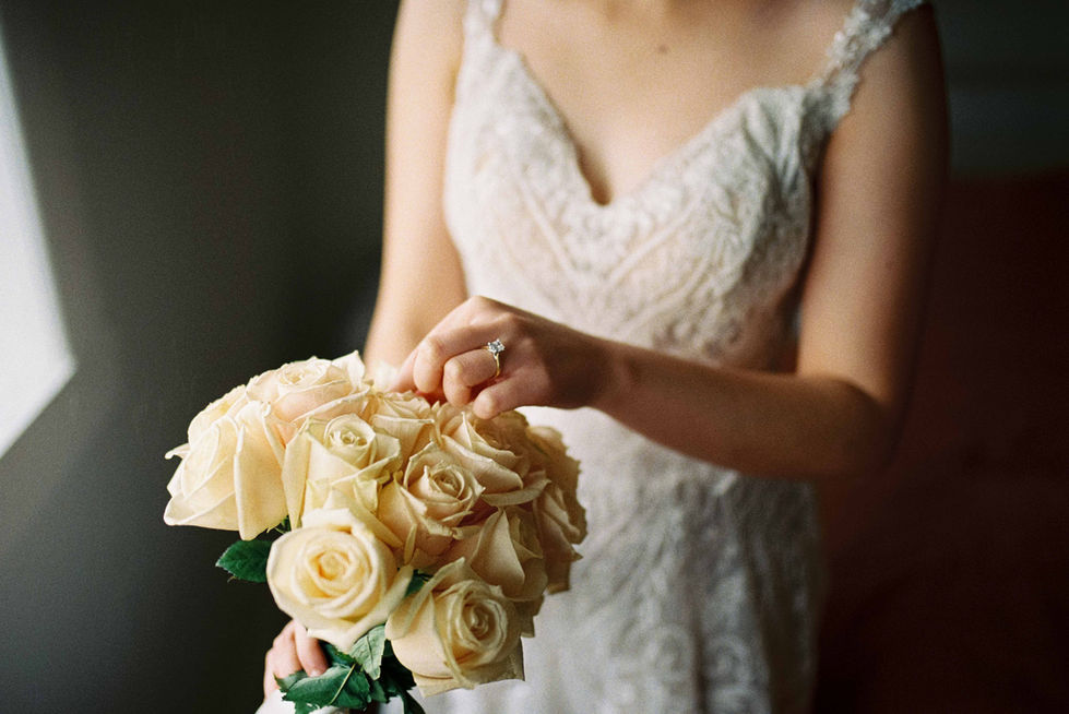 a woman in a wedding dress is holding a bouquet of white roses