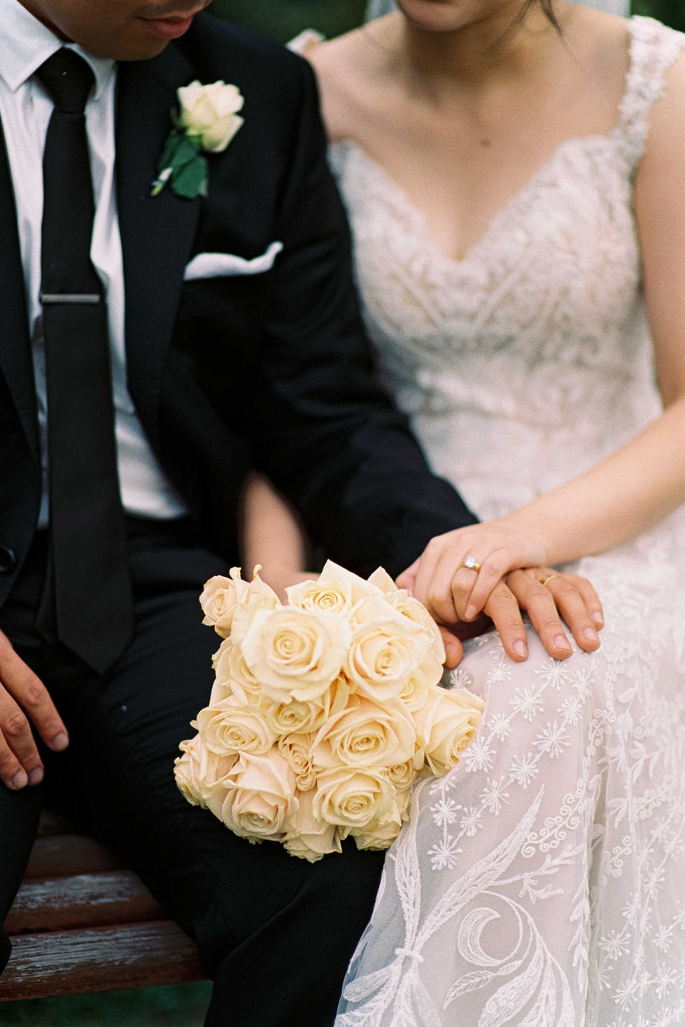 a bride and groom are holding hands and the bride is holding a bouquet of white roses