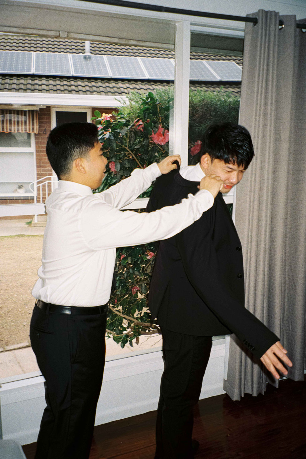 a man in a white shirt helps another man in a black suit