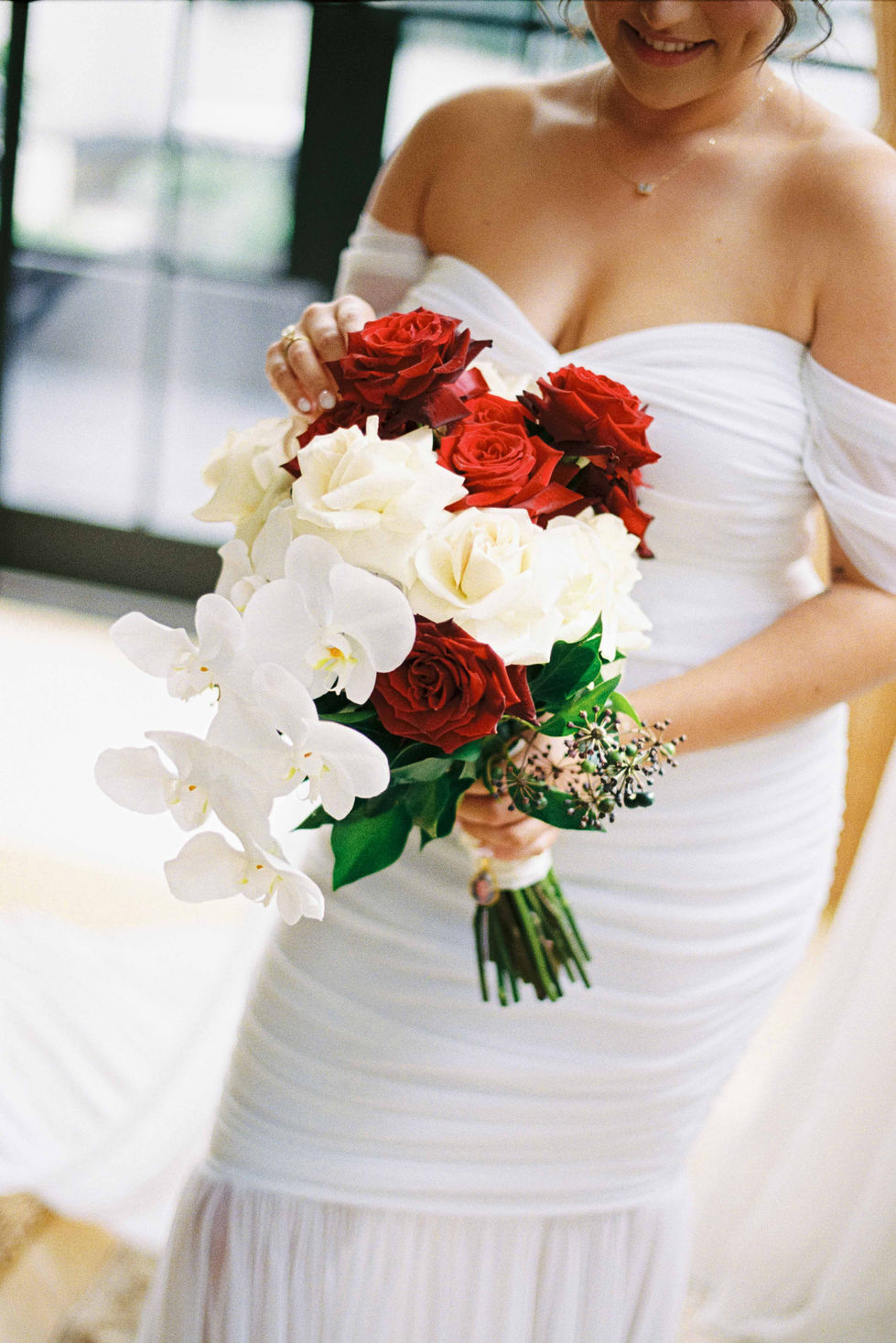 a woman in a white dress is holding a bouquet of red and white flowers