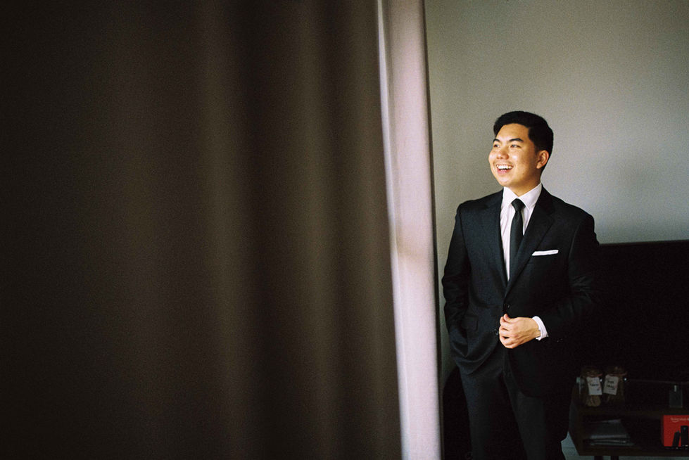 a man in a suit and tie stands in front of a window