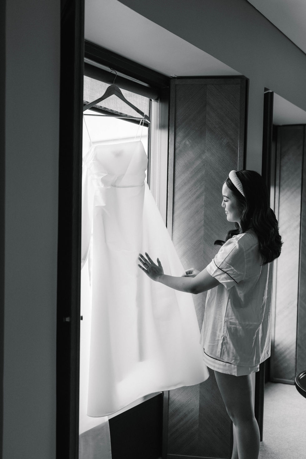 a woman is looking at a white dress hanging on a hanger