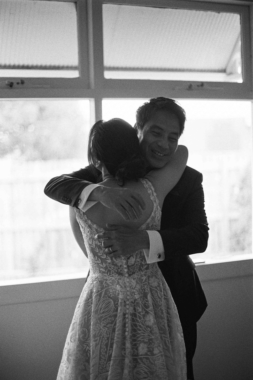 a man in a suit is hugging a woman in a wedding dress