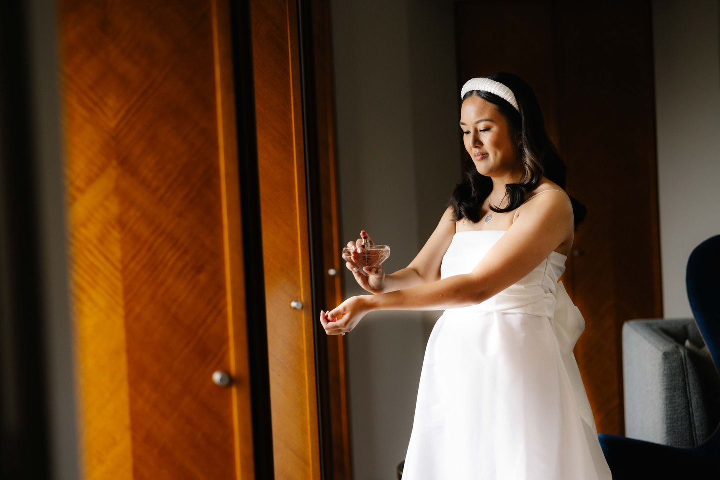 a woman in a white dress is spraying perfume on her wrist
