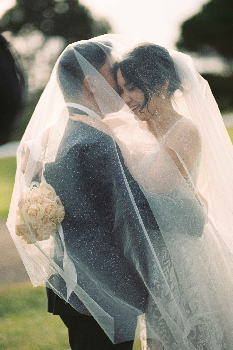 a bride and groom are kissing under a veil