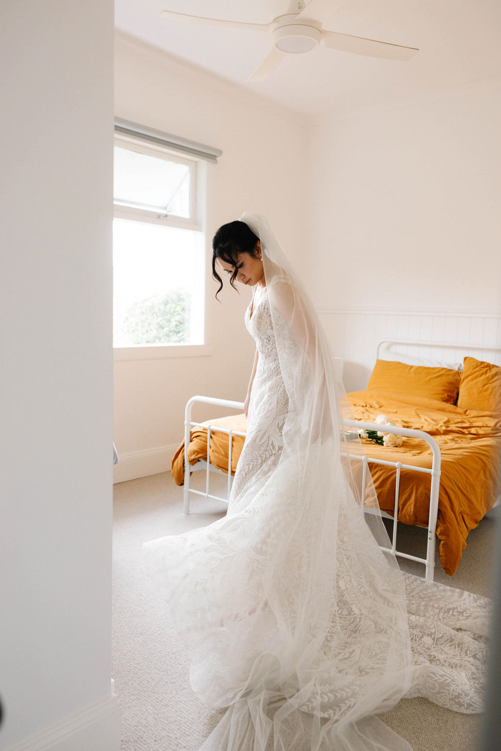 a woman in a wedding dress is standing in front of a bed