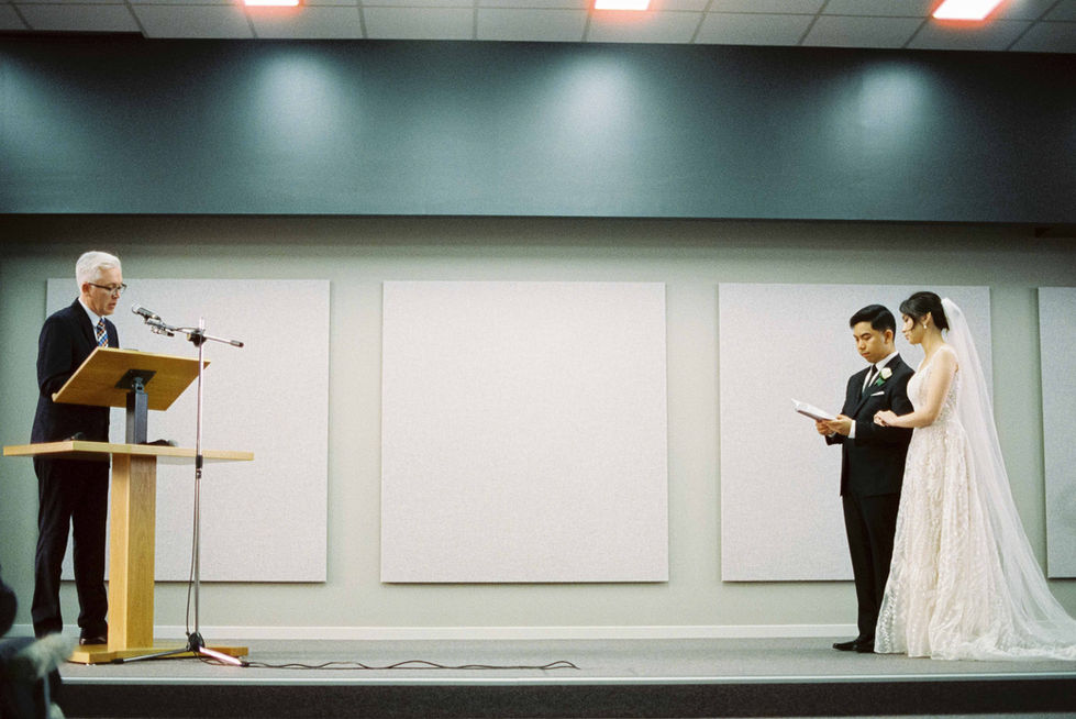 a man in a suit stands on a stage holding a piece of paper