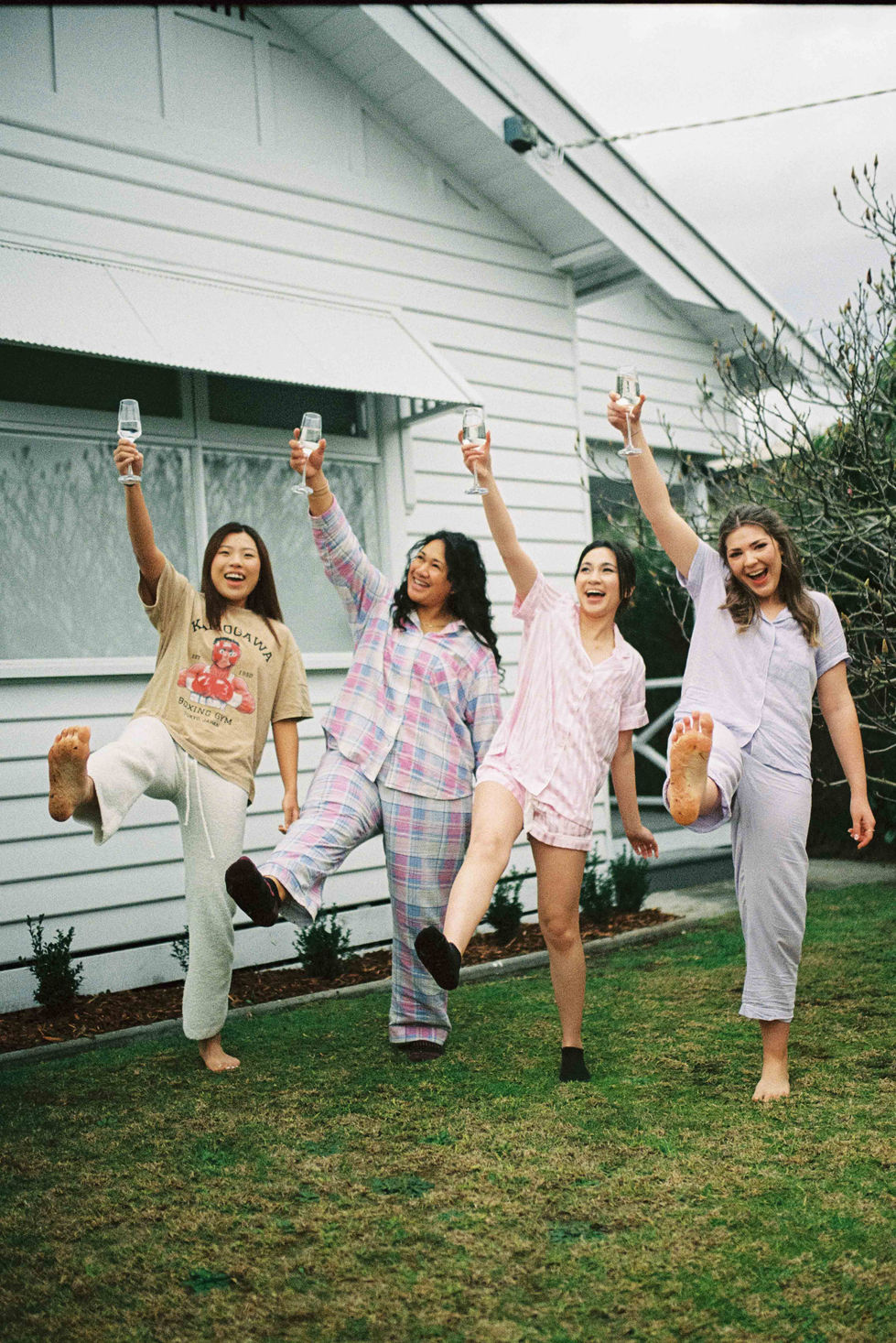 four women in pajamas are raising their glasses in the air