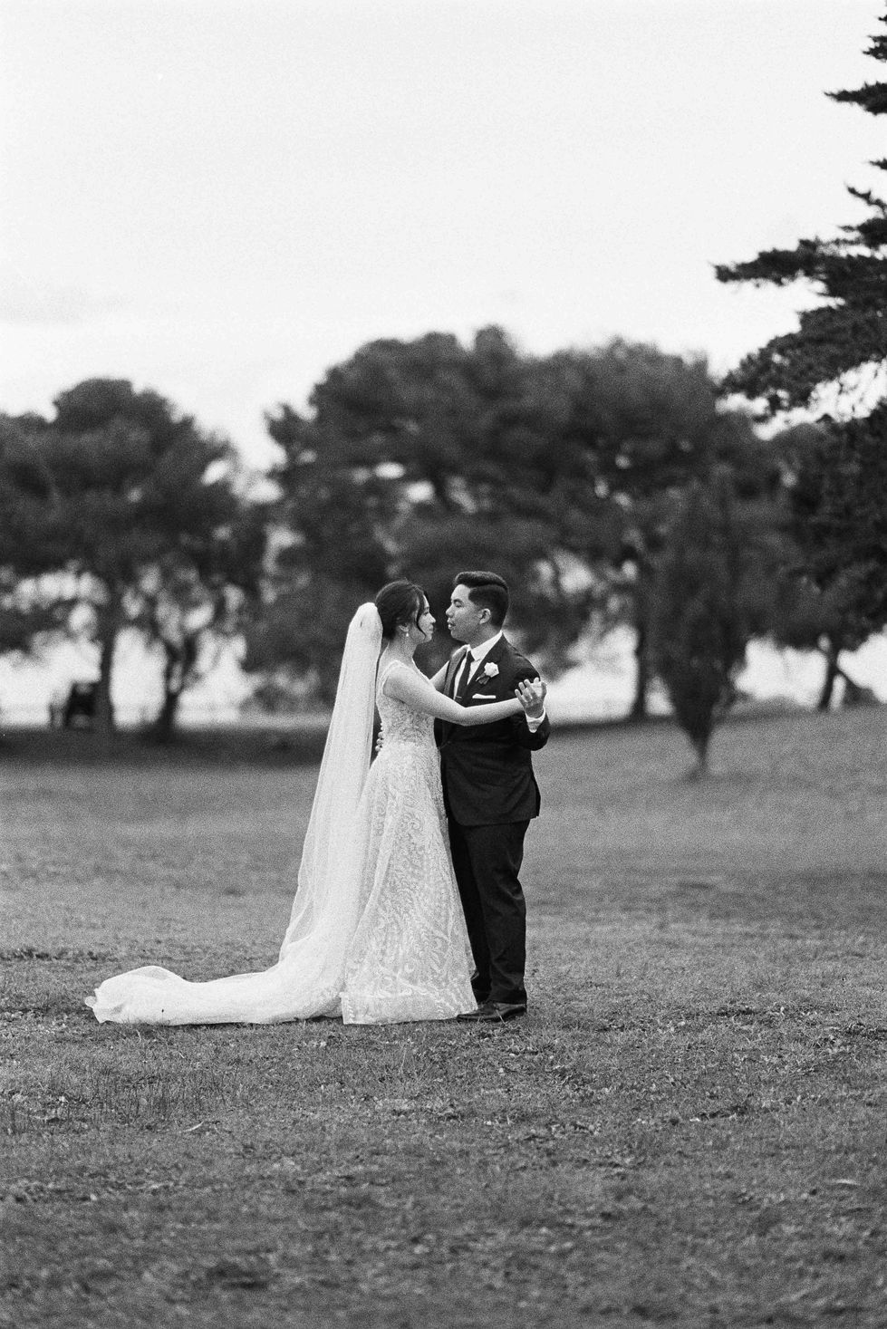 a black and white photo of a bride and groom in a field