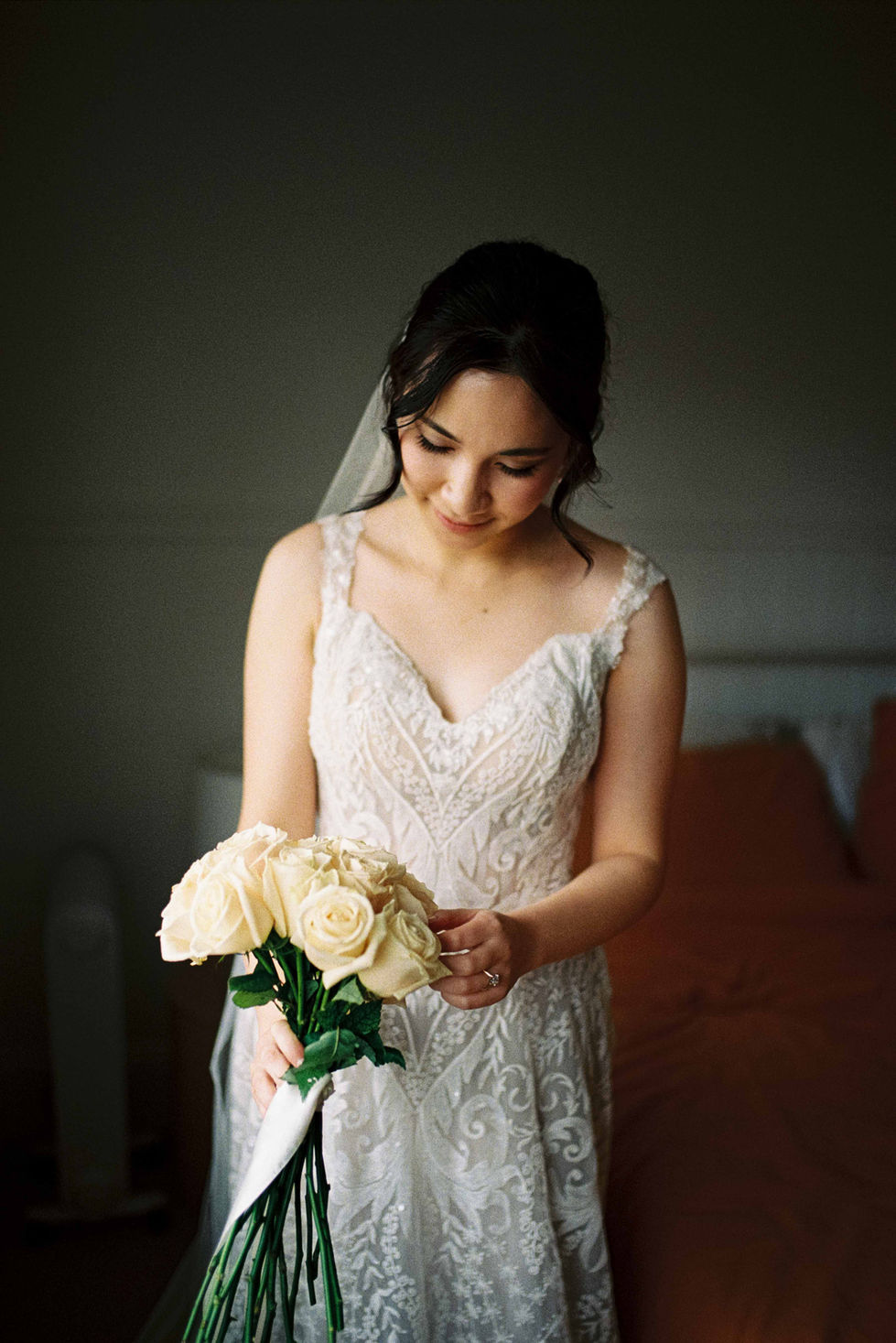 a woman in a wedding dress is holding a bouquet of white roses