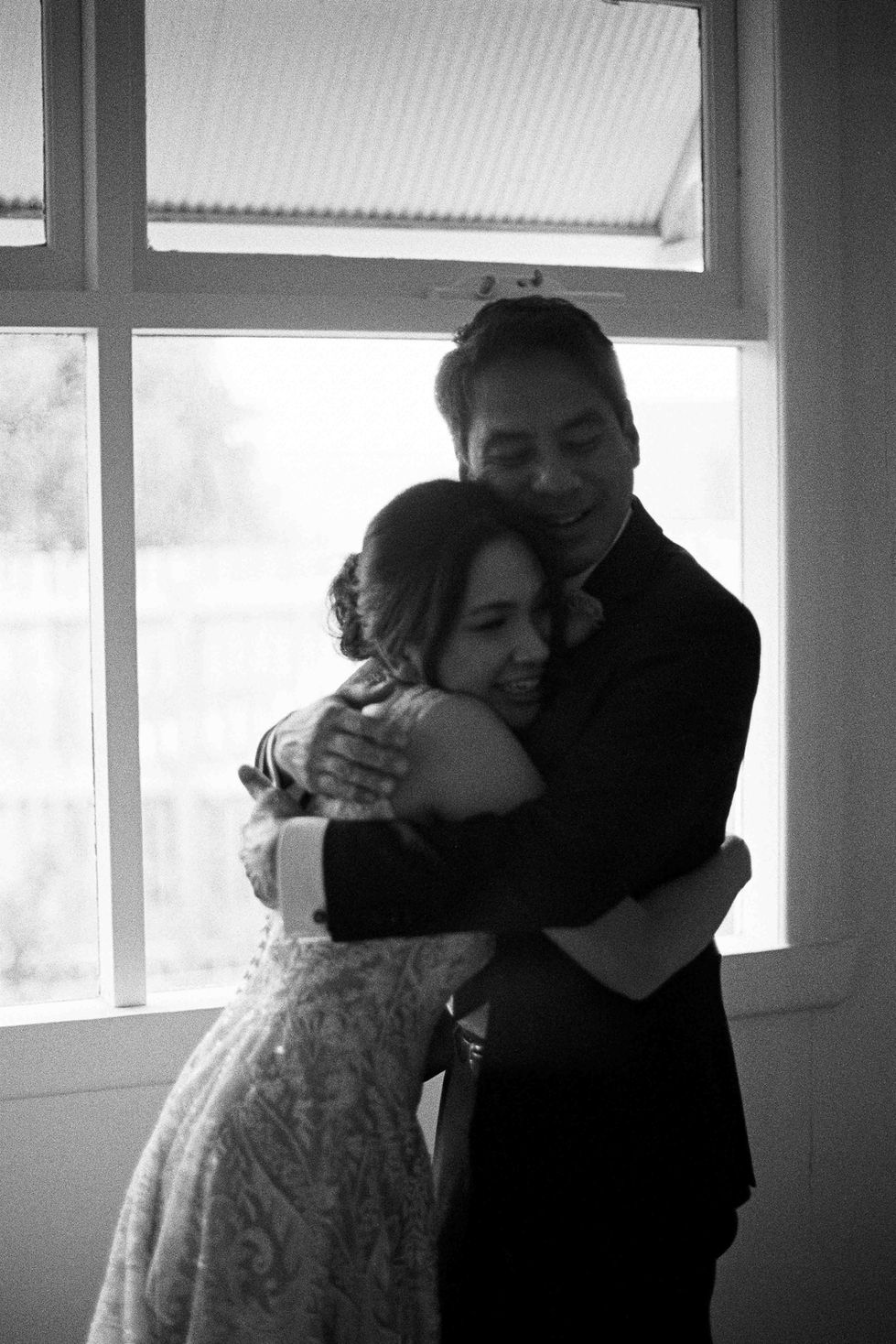 a man and woman hugging in front of a window
