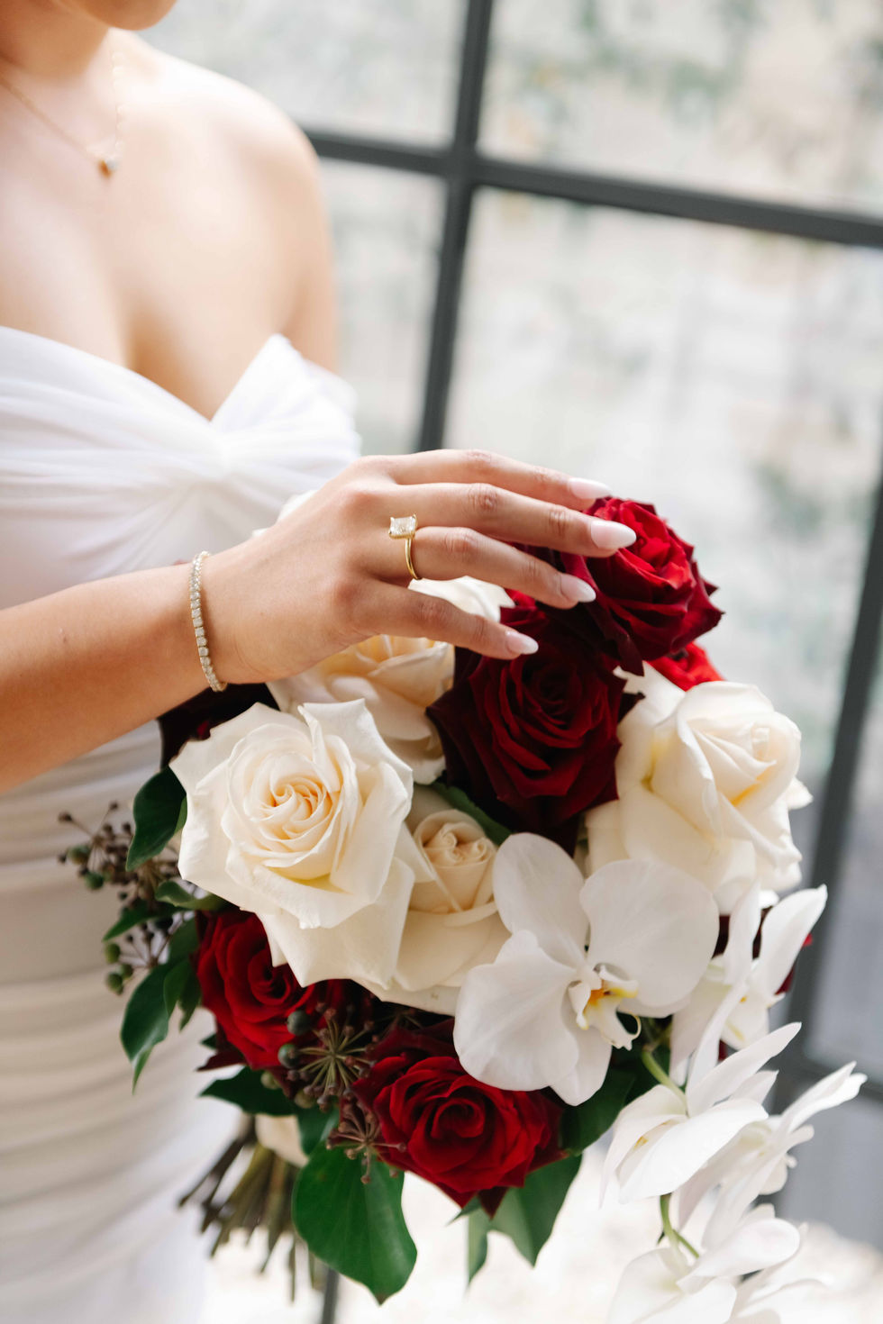 a woman in a white dress is holding a bouquet of red and white roses