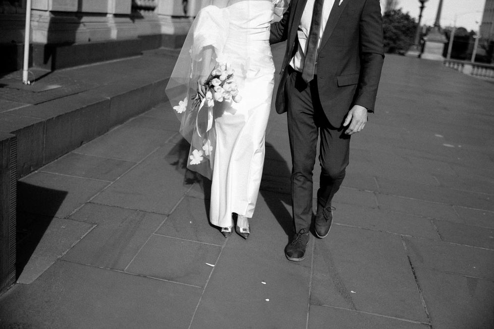 a black and white photo of a bride and groom walking
