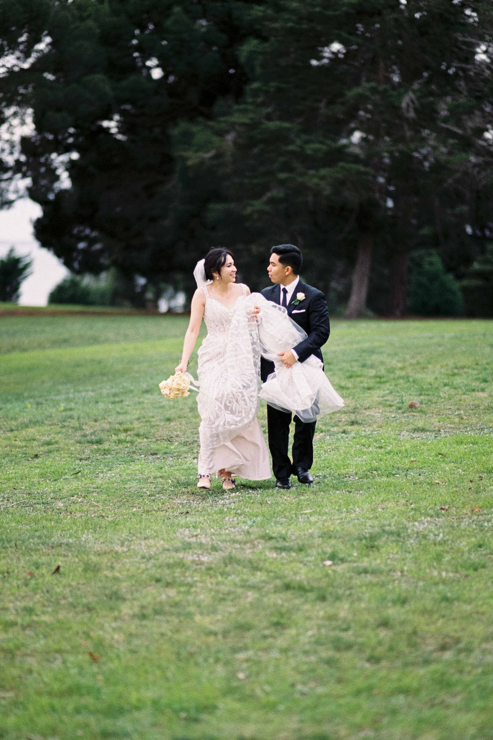 a bride and groom are walking through a grassy field