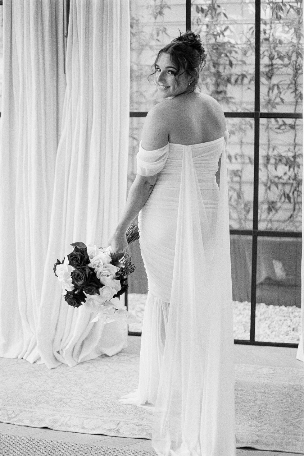 a woman in a white dress is holding a bouquet of flowers