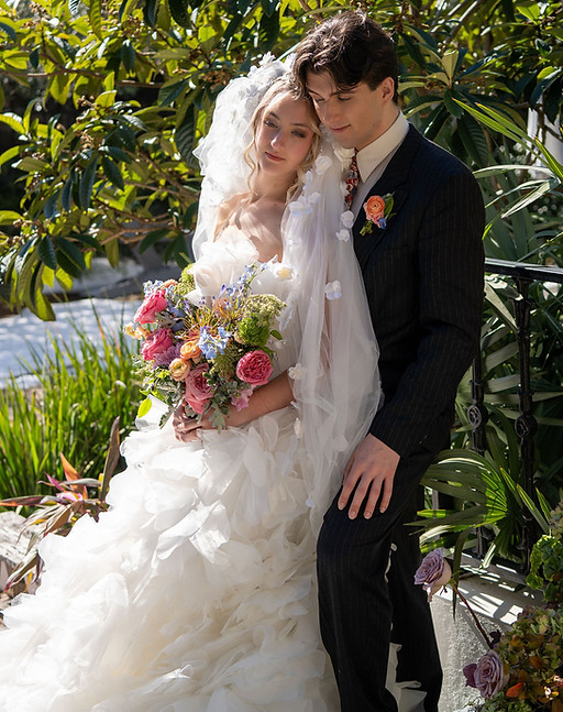 Floral wedding dress with flower veil. Mens suit in black, flower bouquet.