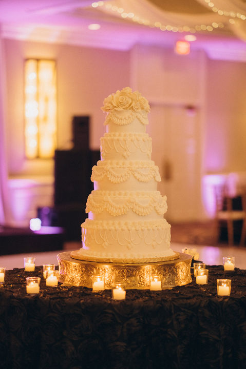Elegant tiered wedding cake surrounded by candles, captured by engagement photography
