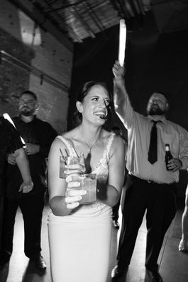 Bride smiling, holding a drink; three men; low light, wedding photography Chicago.
