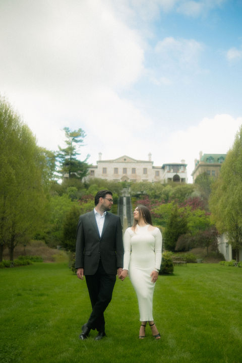 Couple holding hands in a park with a building, engagement photography, monograin